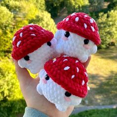 two small crocheted gnomes are held in the palm of someone's hand