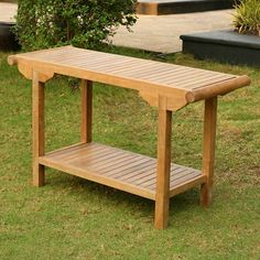 a wooden table sitting on top of a grass covered field next to a bush and shrubbery