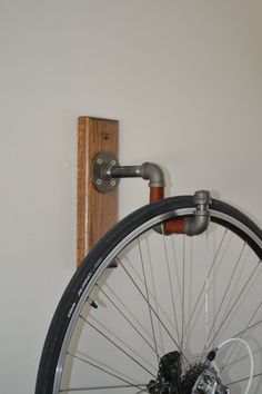 an old bicycle wheel is mounted to the wall with a hook on it's side