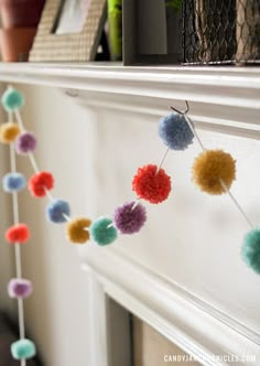 colorful pom - poms are hanging on the mantle