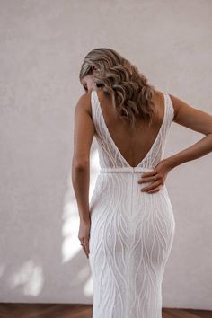 a woman in a white wedding dress with her back to the camera, looking down