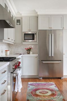 a kitchen with white cabinets and stainless steel appliances, including a rug on the floor