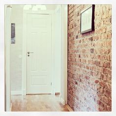 a white door and brick wall in a room with hard wood flooring on the side