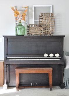 a piano sitting in front of a window next to a vase with flowers on it