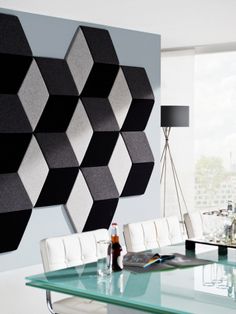 a glass table with white chairs in front of a black and white wall mounted art piece