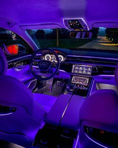 the interior of a car with purple lighting and leather seats, along with electronic controls