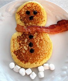 two pancakes on a plate with bacon and marshmallows in the shape of snowmen