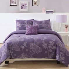 a bed with purple comforters and pictures on the wall