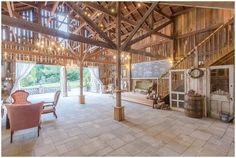 the inside of a large barn with lots of wood and lights hanging from it's ceiling