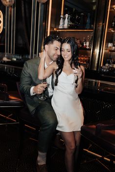 a man and woman sitting next to each other at a bar posing for the camera