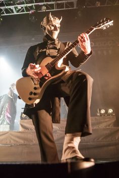 a man with a mask playing an electric guitar