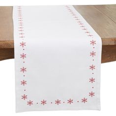 a white table runner with red snowflakes on it and a wooden bench in the background