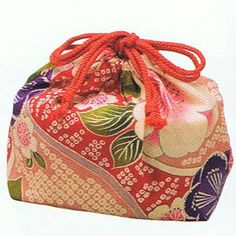 a red and white flowered bag on a white background with an orange string hanging from it