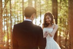 a bride and groom are standing in the woods looking into each other's eyes