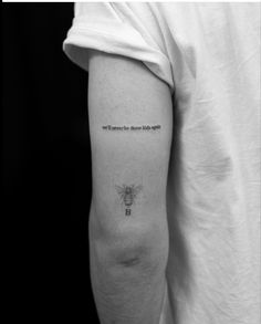 a black and white photo of a person's arm with a bee tattoo on it