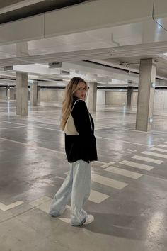 a woman is standing in an empty parking garage with her back to the camera and she has long blonde hair