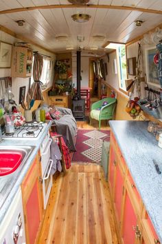 the inside of a camper with wood floors and walls, including a stove top oven