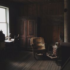 an old chair sitting in front of a window next to a wooden table and chairs