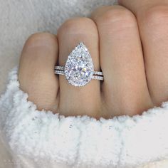 a woman's hand with a diamond ring on top of her finger and a white towel in the background