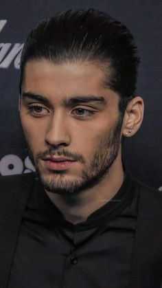 a close up of a person wearing a black shirt and tie with his hair pulled back