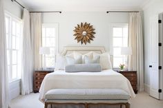 a bedroom with white bedding and beige curtains