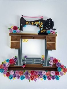 a sewing machine sitting on top of a wooden table next to flowers and a bench