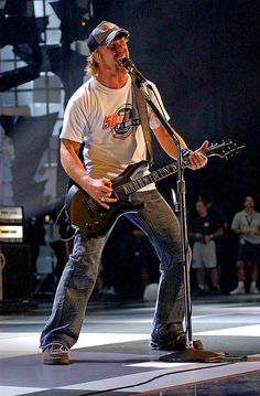 a man with a guitar standing in front of a microphone