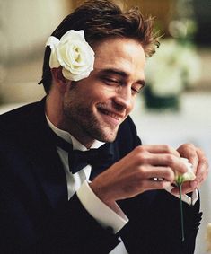 a man in a tuxedo is holding a flower