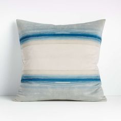 a blue and white striped pillow sitting on top of a table next to a wall