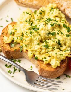 an egg salad is on top of toast and has a fork in front of it