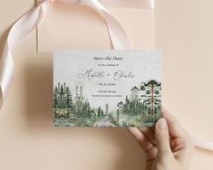 someone holding up a save the date card in front of a pink background with white ribbon