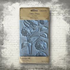 an image of a flower mold on a brick wall with it's packaging in the foreground