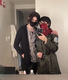 two people standing in front of a mirror wearing face masks