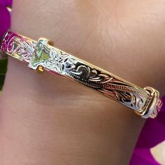 Everyone was asking for a Hawaiian Scroll Bangle that didn’t require a size, so we designed a new one just for you! This beautiful adjustable bangle is Gold Plated over Brass so it’s super affordable! Exquisite Hawaiian scrollwork adorns the whole bracelet as it adjusts from size 7.5 all the way up to size 9. The comfortable design tapers from 10mm to 5mm and is great for all ages! 14K gold plated over Brass Adjusts from size 7.5 to size 9 Tapered Design from 10mm to 5mm wide Hand engraved Hawai Adjustable Engraved Bangle Bracelet, Adjustable Bangle Jewelry For Gift, Adjustable Bangle Jewelry As Gift, Adjustable Engraved Bangle Jewelry, Engraved Adjustable Bangle Jewelry, Adjustable Green Engraved Bracelets, Adjustable Engraved Bangle, Hawaiian Heirloom Jewelry, Heirlooms Jewelry