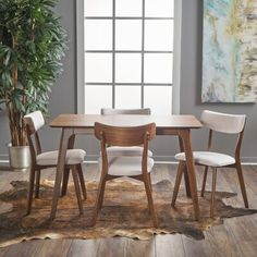 a dining room table with chairs and a potted plant in the corner next to it