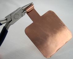 a pair of scissors cutting into a piece of copper