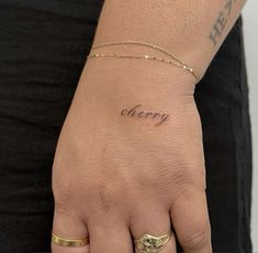 a woman's hand with the word cherry tattooed on her left wrist and gold bracelet