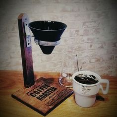 a cup of coffee next to a drink dispenser on a wooden table