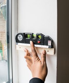 a person is pressing the button on a wall mounted power strip in front of a window