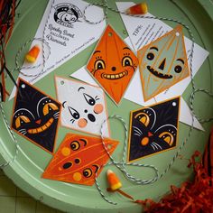 several halloween cards on a green plate with orange and black decorations hanging from it's sides