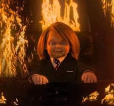 the doll is wearing a suit and tie in front of a large fire filled background