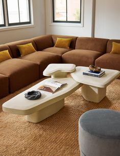 a living room filled with lots of furniture next to a large window on top of a carpeted floor