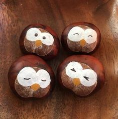 four chocolate donuts with white frosting on them sitting on top of a wooden table