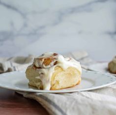 a white plate topped with cinnamon rolls covered in icing