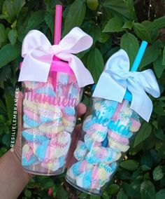 two handmade candy jars with bows and name stickers on them, one is pink and the other is blue