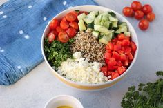 a white bowl filled with vegetables next to a blue towel and two bowls of dressing