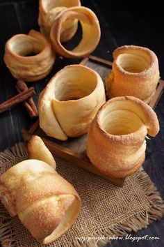 cinnamon buns on a wooden tray with cinnamon sticks in the middle and cinnamon sticks next to them