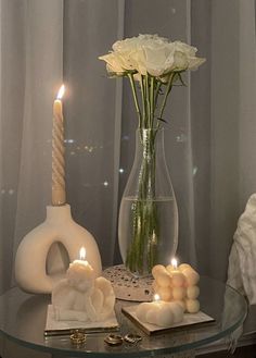 a glass table with candles, flowers and other items on it in front of a window