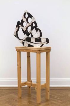 a wooden table topped with a black and white sculpture sitting on top of it's side