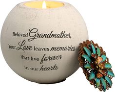 a candle that is sitting next to a vase with a flower on the inside and a quote written in it